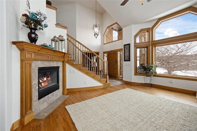 foyer entrance with baseboards, a premium fireplace, stairway, a high ceiling, and light wood-style floors