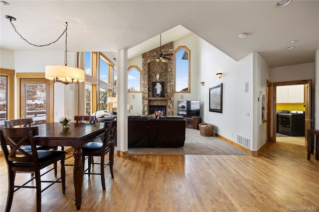 dining room featuring hardwood / wood-style floors, a fireplace, washer / clothes dryer, and ceiling fan