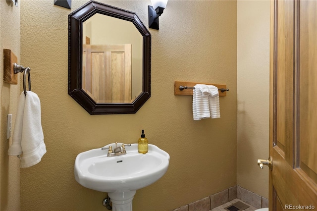 bathroom with a textured wall and a sink