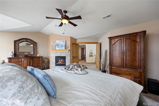 carpeted bedroom with a fireplace, vaulted ceiling, and ceiling fan