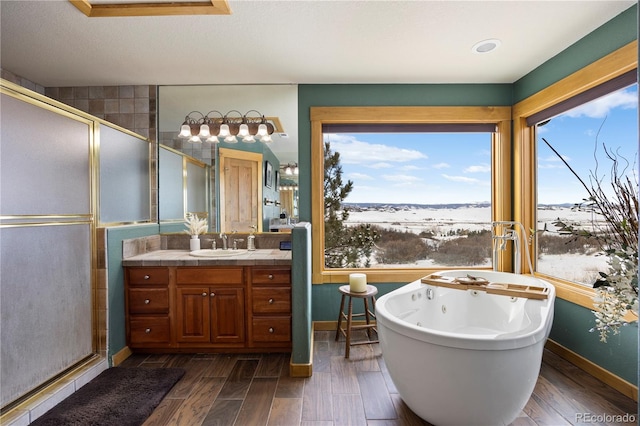 full bathroom featuring a stall shower, a freestanding bath, vanity, and wood finished floors