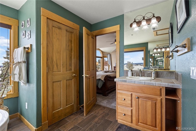 ensuite bathroom featuring wood tiled floor, vanity, baseboards, and ensuite bathroom