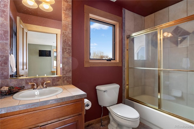 full bathroom with bath / shower combo with glass door, vanity, toilet, and tasteful backsplash