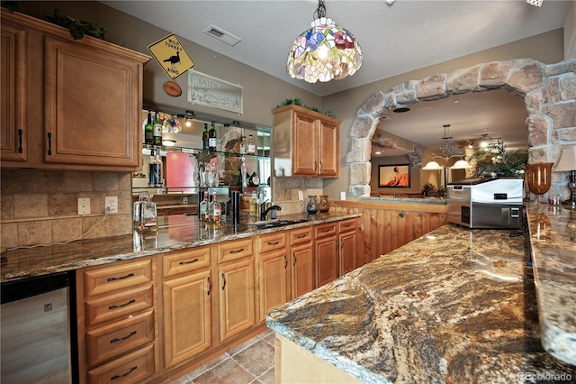 kitchen featuring backsplash, decorative light fixtures, a textured ceiling, and stone counters