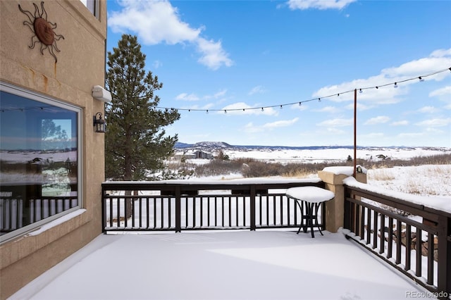 snow covered deck with a mountain view