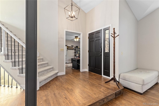 foyer entrance with wood-type flooring, high vaulted ceiling, and a chandelier