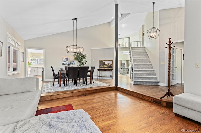 living room with high vaulted ceiling, a chandelier, and hardwood / wood-style floors