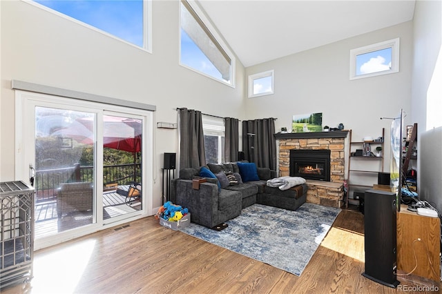 living room featuring hardwood / wood-style floors, a stone fireplace, and a towering ceiling