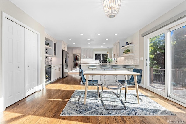 dining area with beverage cooler and light hardwood / wood-style flooring