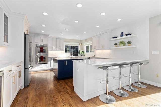 kitchen with a kitchen island, white cabinetry, appliances with stainless steel finishes, and a breakfast bar area