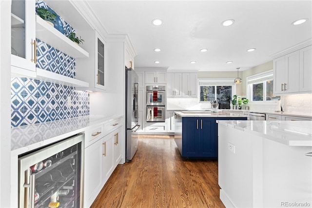 kitchen featuring wine cooler, blue cabinetry, white cabinetry, hanging light fixtures, and appliances with stainless steel finishes