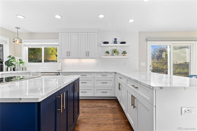 kitchen with white cabinetry, dark hardwood / wood-style floors, pendant lighting, and light stone counters