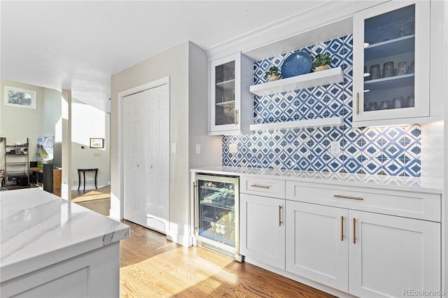 kitchen featuring white cabinetry, wine cooler, and light stone counters