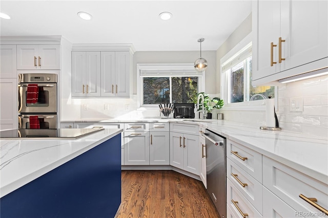 kitchen with light stone countertops, appliances with stainless steel finishes, white cabinets, and decorative light fixtures