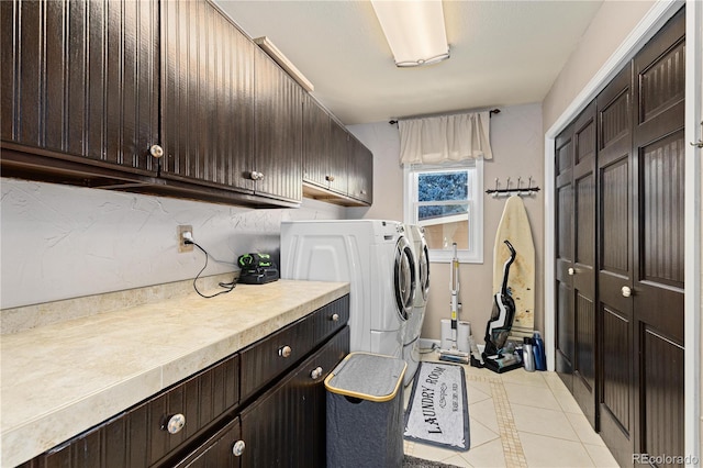 laundry area featuring light tile patterned floors, cabinets, and washing machine and clothes dryer