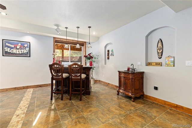 dining room featuring bar and a textured ceiling