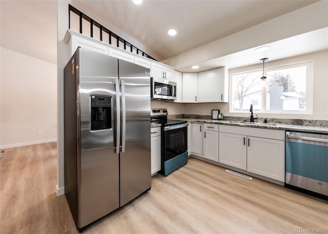 kitchen featuring pendant lighting, appliances with stainless steel finishes, sink, white cabinetry, and light stone counters