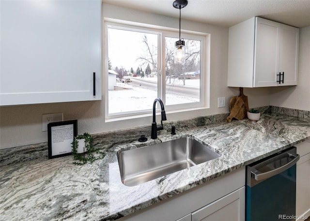 kitchen featuring light stone countertops, dishwasher, white cabinets, decorative light fixtures, and sink