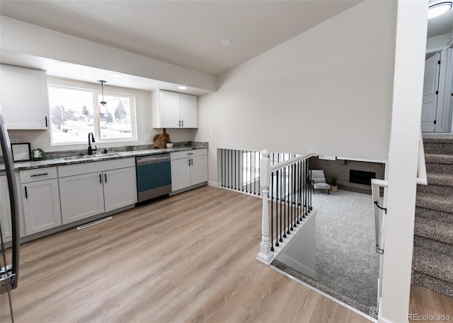 kitchen with dishwasher, white cabinetry, sink, stone countertops, and light wood-type flooring