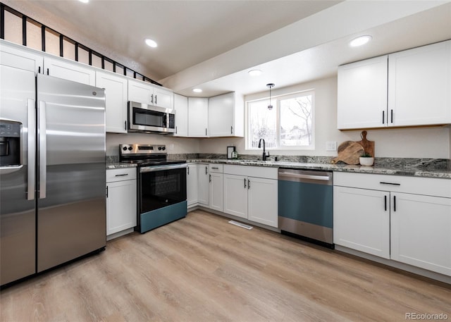 kitchen featuring pendant lighting, white cabinets, stainless steel appliances, and vaulted ceiling