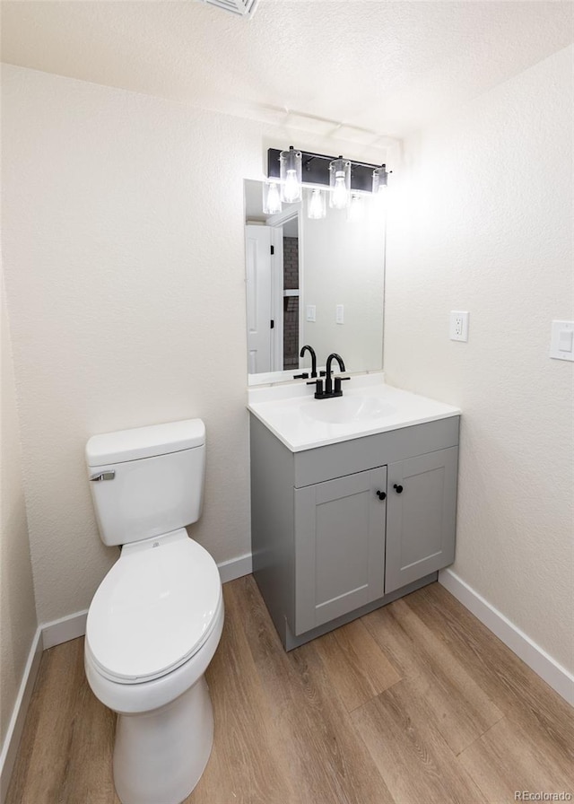 bathroom featuring hardwood / wood-style flooring, a textured ceiling, toilet, and vanity