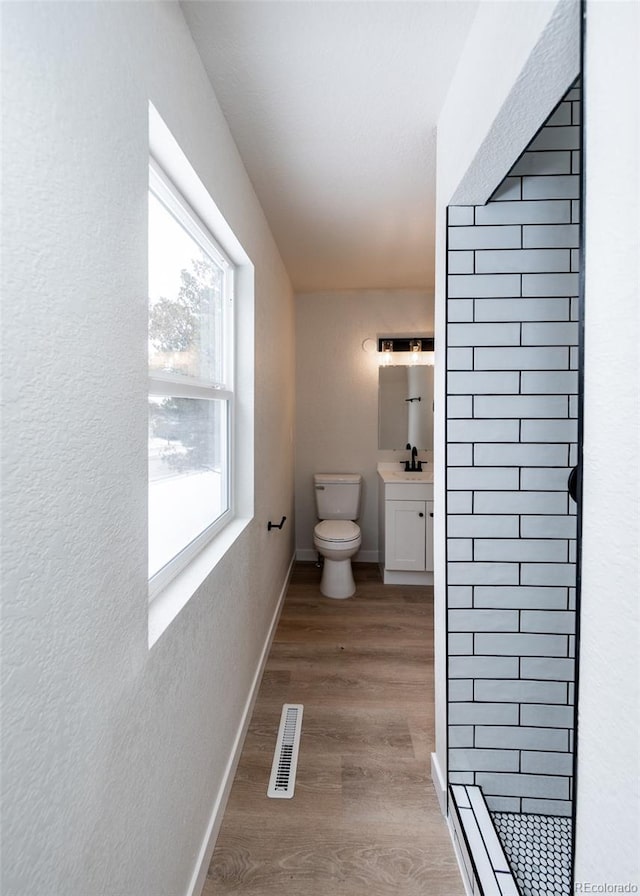 bathroom with a shower, hardwood / wood-style floors, toilet, and vanity