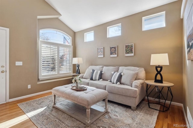 living room with light wood-style floors, high vaulted ceiling, and baseboards