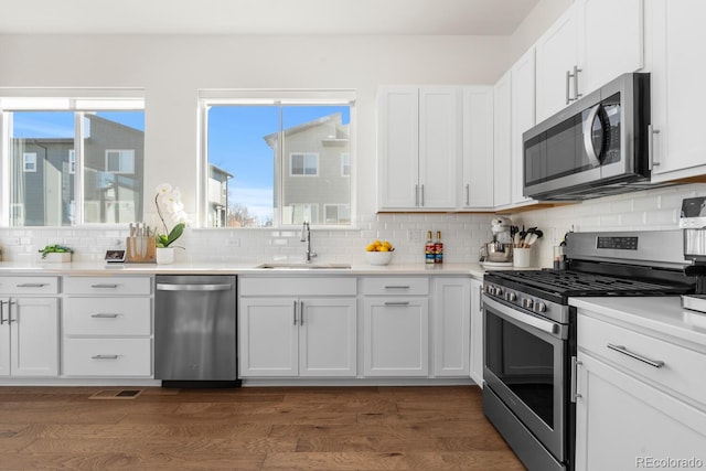 kitchen with stainless steel appliances, light countertops, a sink, and white cabinetry