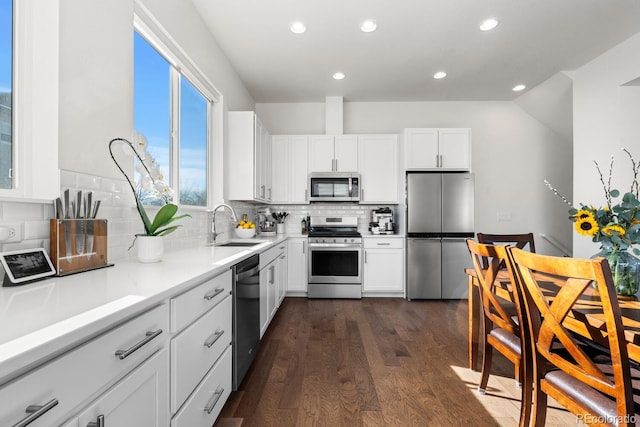 kitchen featuring dark wood-style flooring, stainless steel appliances, light countertops, white cabinetry, and a sink