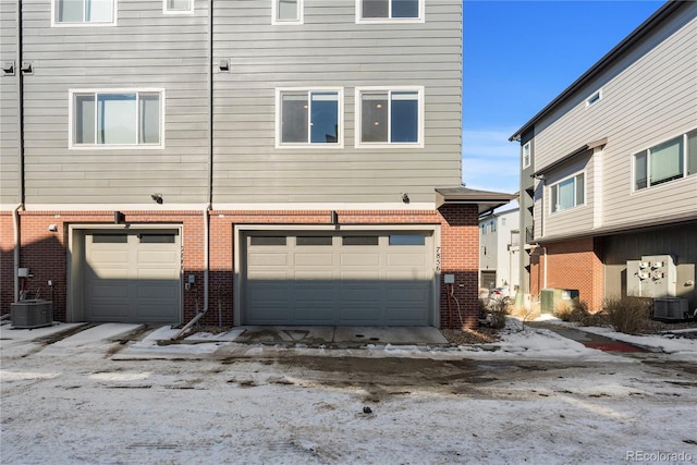 exterior space featuring brick siding, an attached garage, and central air condition unit