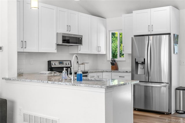 6604 S Dahlia Cir, Centennial, CO 80121 - kitchen with stainless steel appliances, a peninsula, white cabinetry, backsplash, and light stone counters