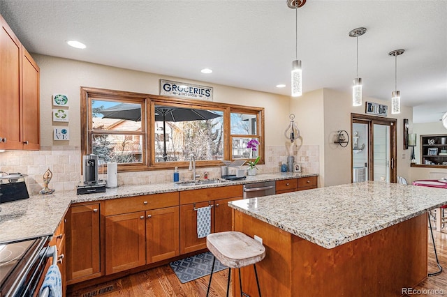 kitchen featuring light stone counters, a kitchen bar, a center island, and sink