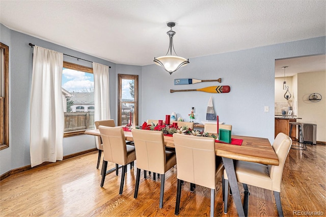 dining area with light hardwood / wood-style flooring and a textured ceiling