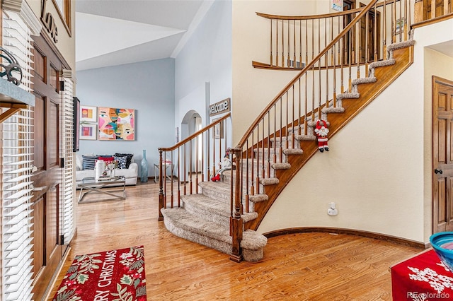 foyer entrance with wood-type flooring and high vaulted ceiling