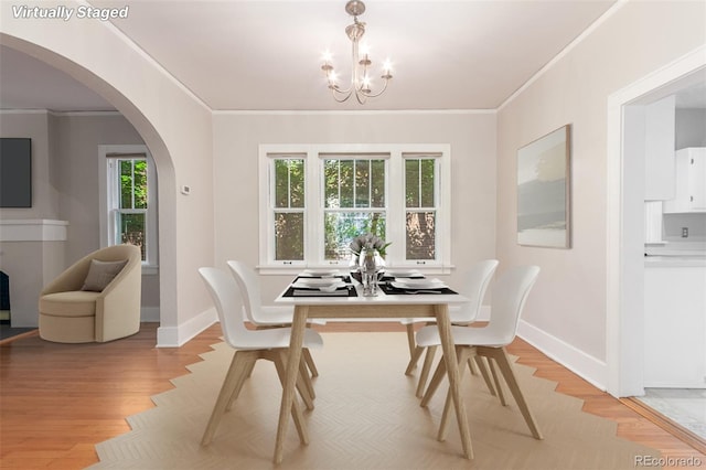 dining area featuring light wood-type flooring, crown molding, and a chandelier