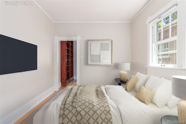 bedroom featuring crown molding, a walk in closet, a closet, and wood-type flooring