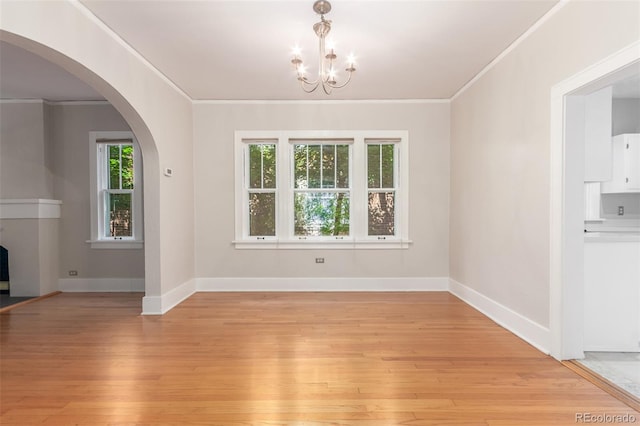 unfurnished dining area featuring crown molding, light hardwood / wood-style flooring, and an inviting chandelier