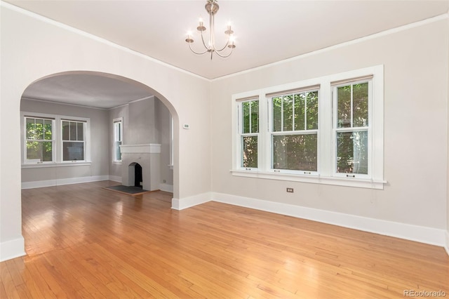 unfurnished living room featuring hardwood / wood-style floors, a notable chandelier, and ornamental molding