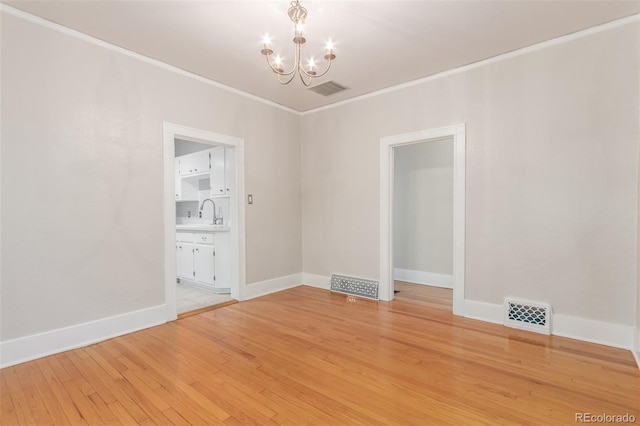 spare room featuring ornamental molding, an inviting chandelier, and light hardwood / wood-style floors