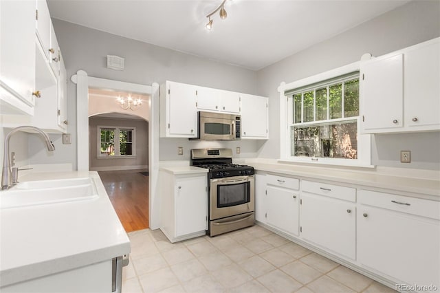 kitchen with white cabinets, light wood-type flooring, stainless steel appliances, and sink