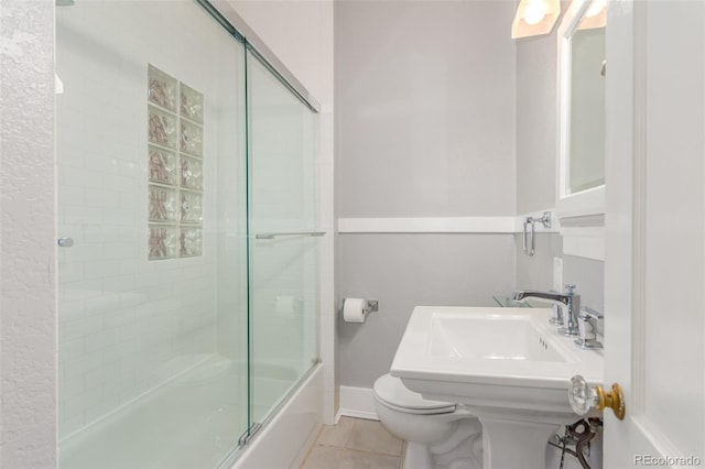 bathroom with shower / bath combination with glass door, tile patterned flooring, and toilet