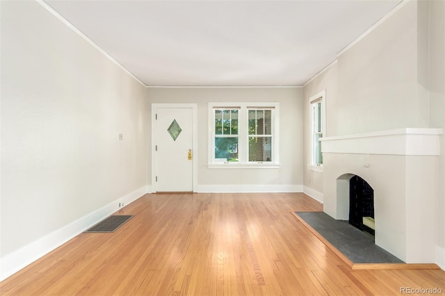 unfurnished living room featuring light wood-type flooring and ornamental molding