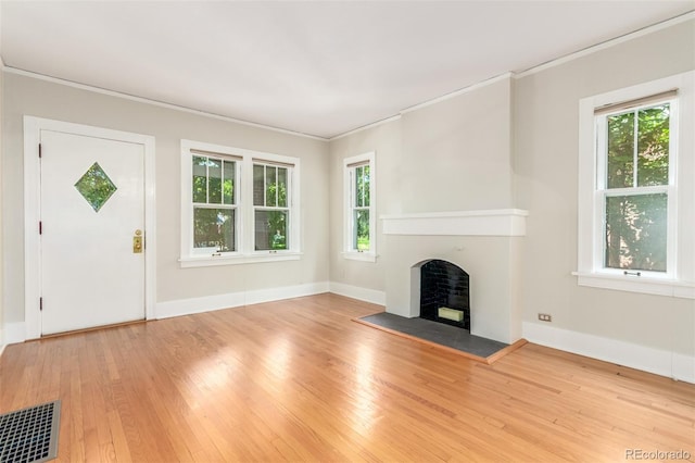 unfurnished living room featuring hardwood / wood-style flooring, plenty of natural light, and ornamental molding