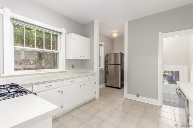 kitchen featuring stainless steel fridge, light tile patterned floors, dishwashing machine, and white cabinetry