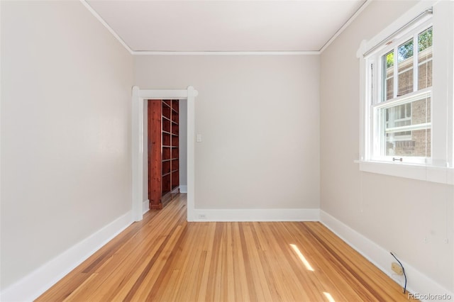 spare room featuring crown molding, plenty of natural light, and light hardwood / wood-style floors