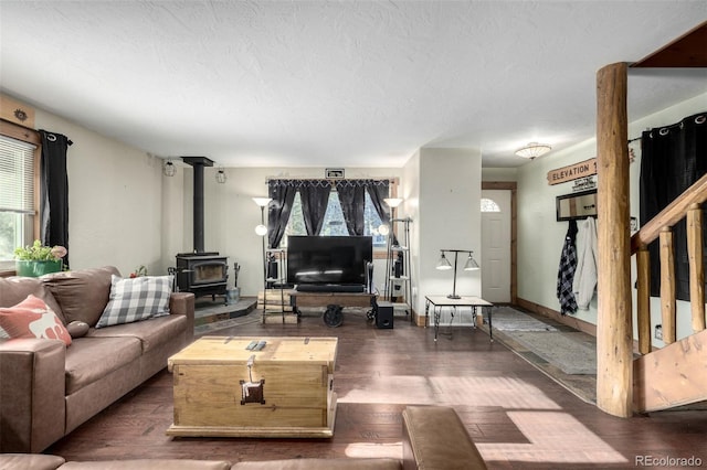 living room with dark wood-type flooring, a healthy amount of sunlight, and a wood stove