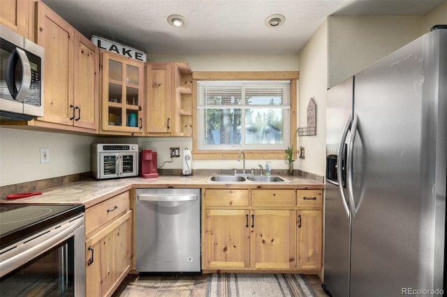 kitchen with stainless steel appliances, light brown cabinetry, and sink