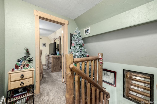 hall with vaulted ceiling, a textured ceiling, and carpet flooring