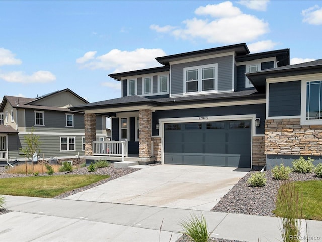 17843 W 93rd Pl, Arvada, CO 80007 - prairie-style house featuring a porch, stone siding, an attached garage, and concrete driveway