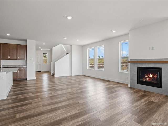 17843 W 93rd Pl, Arvada, CO 80007 - unfurnished living room with healthy amount of natural light, dark wood-style flooring, a tile fireplace, and recessed lighting